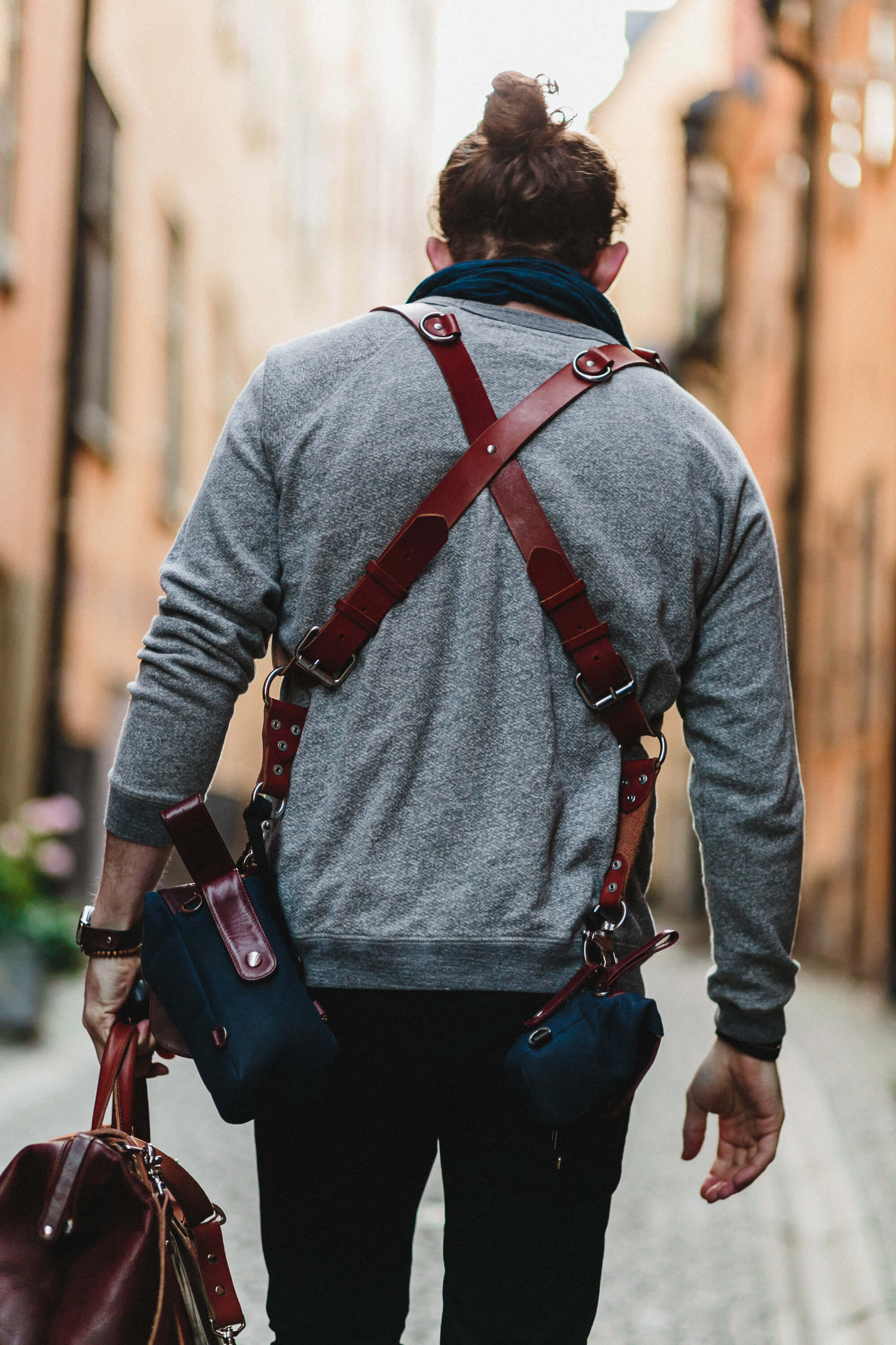 Man walking down a street wearing a leather crossbody bag